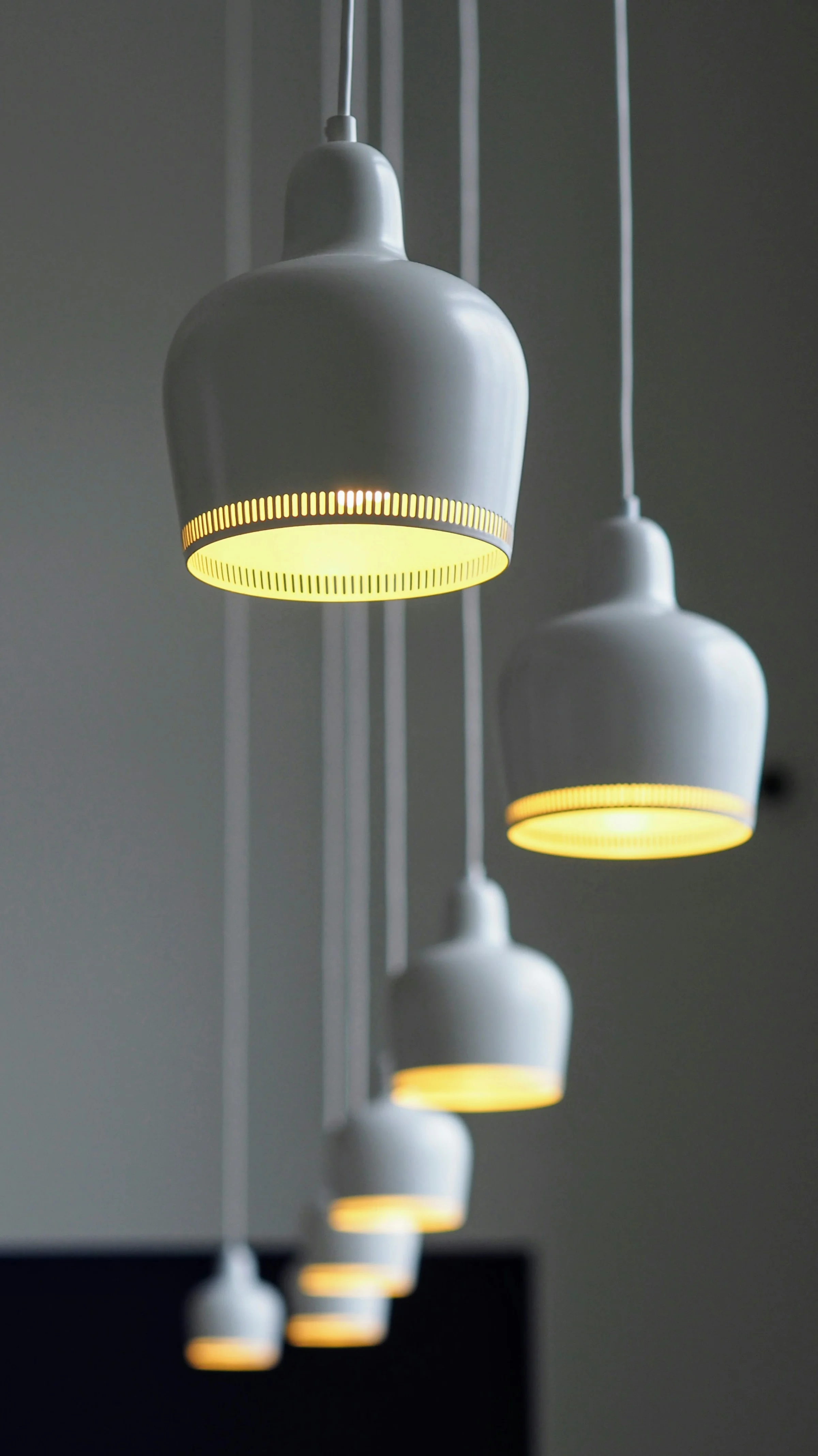 A cascade of white Aalto pendant lamps glowing warmly