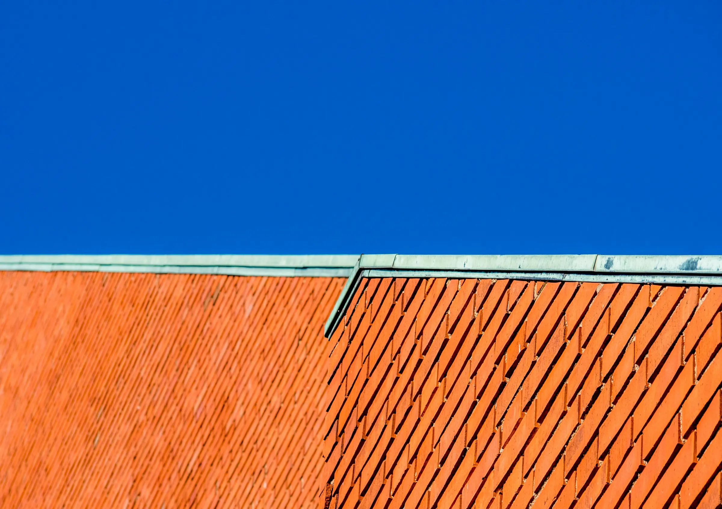 A red-brick rooftop edge against a deep blue sky